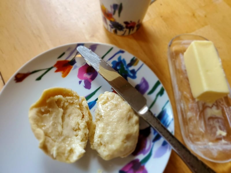 Image of a sliced roll on a plate with buttered smeared on it.