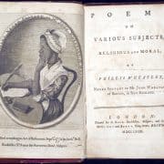 Phillis Wheatley at her desk, one hand under her chin, the other with poised quill.