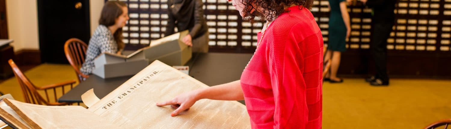 Library Company white woman reference staff and a white woman researcher talk near white women readers looking at large volume and card catalog.