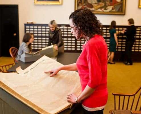 Library Company white woman reference staff and a white woman researcher talk near white women readers looking at large volume and card catalog.