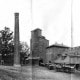 Black and white photograph of exterior of Millbourne Mills in Upper Darby showing horse-drawn wagons lined up outside