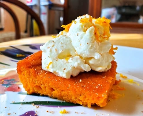 Carrot pudding served with nutmeg, orange zest, and whipped cream
