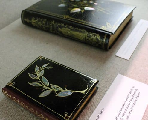 Two examples of papier-mâché bindings laid out in an exhibition case, 2010. Jennifer Rosner, Chief of Conservation.