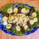 Chicken salad served on a platter with hard boiled eggs and stuffed grape leaves